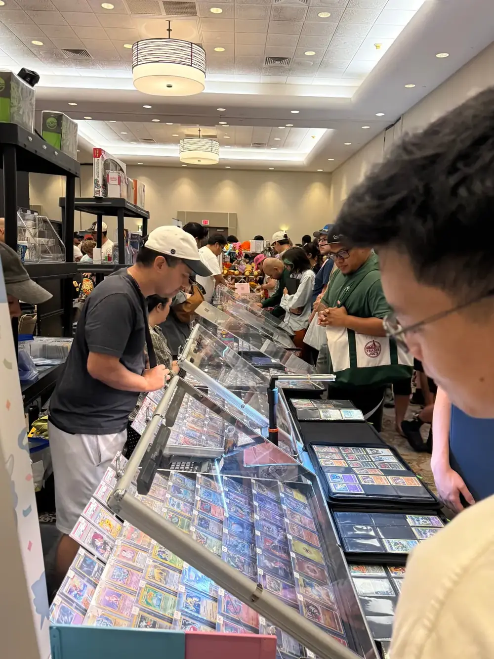 Collectors browsing long rows of Pokémon card display cases and binders at The Cactus TCG Show in Mesa, Arizona