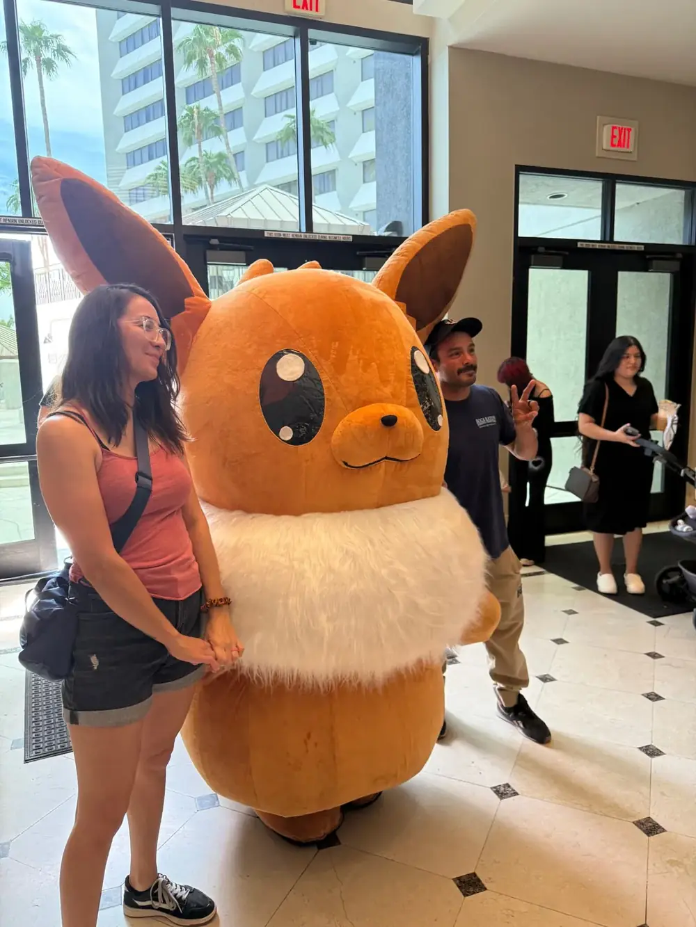 Attendee meeting the life-size Eevee cosplayer in the lobby at The Cactus TCG Show Pokémon card show in Mesa, Arizona