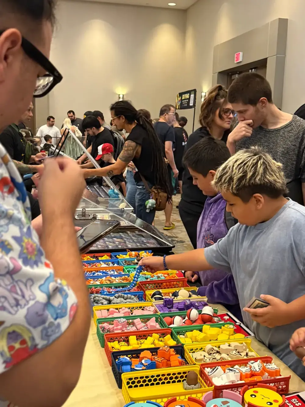 Kids picking Pokémon collectible erasers and toys at a vendor table during The Cactus TCG Show in Mesa, Arizona