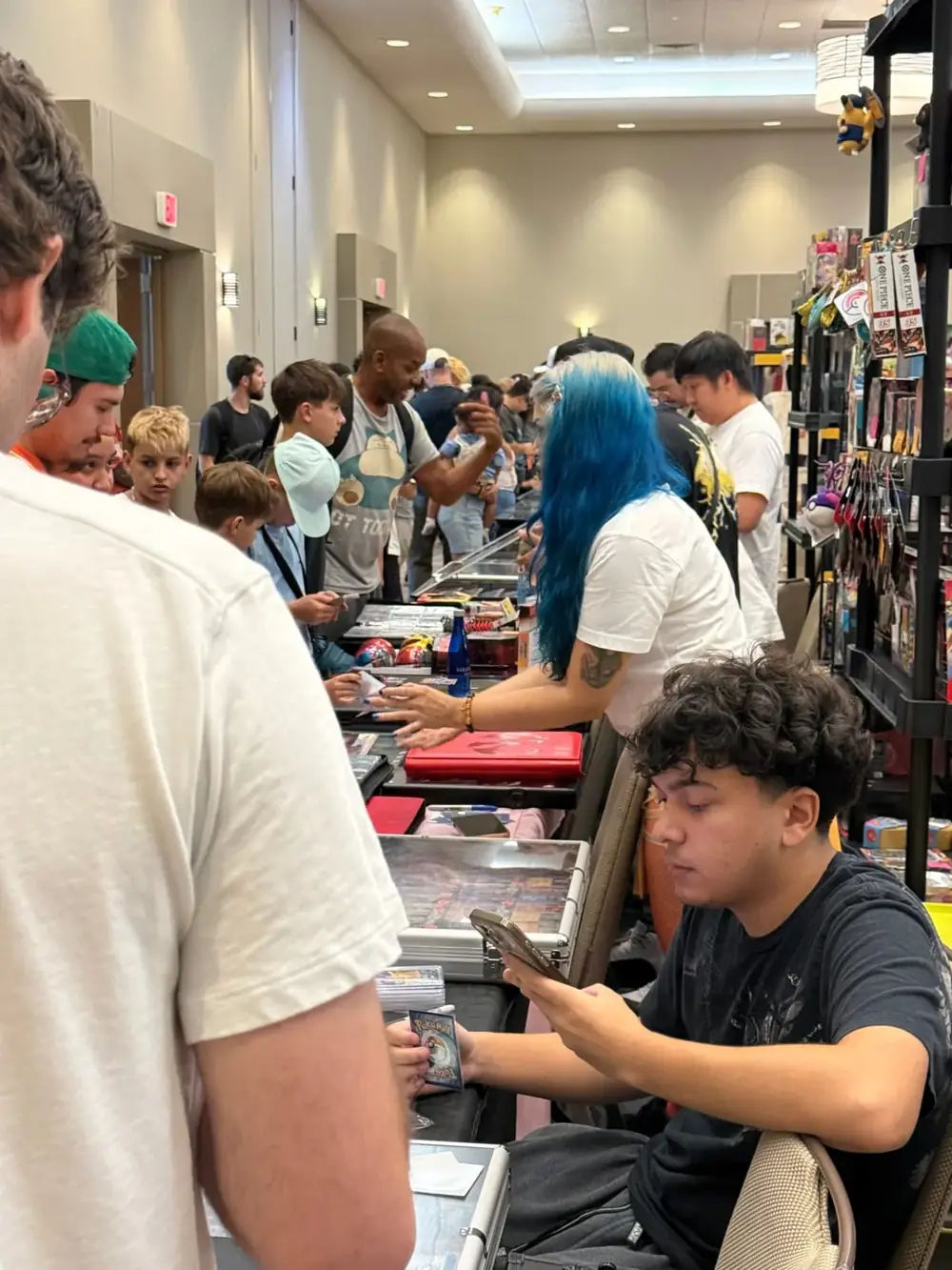 Packed vendor aisle with Pokémon and One Piece card dealers at The Cactus TCG Show in Mesa, Arizona