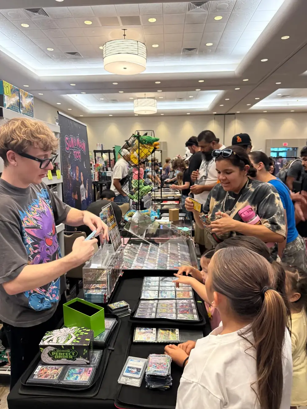 Family shopping Pokémon singles with a vendor at The Cactus TCG Show trading card show in Mesa, Arizona